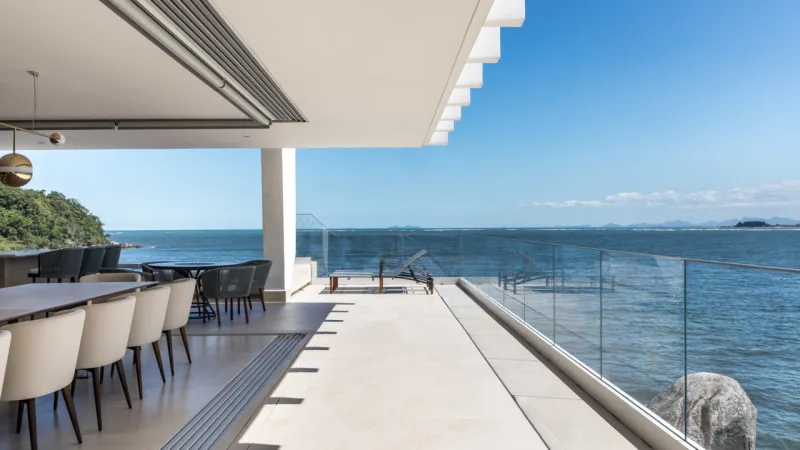 A grande varanda voltada para o mar, que recebeu guarda-corpo em vidro, proporciona momentos de lazer para a família e seus convidados.