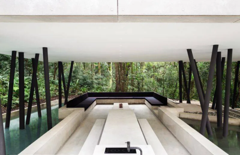 Na parte externa e inferior da casa, o jardim e a área gourmet são conectados e conversam com a topografia do terreno. Foto: MCA Estúdio