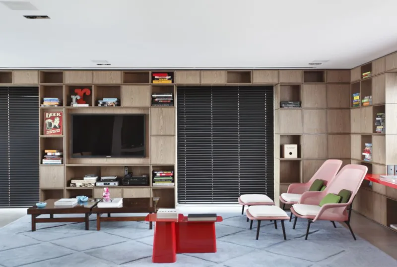 O piso térreo de um apartamento duplex em São Paulo ganhou cara nova depois que o arquiteto Guilherme Torres resolveu “vestir” o lugar com uma estante de parede inteira. Feita em MDF e revestida com folha de carvalho, com nichos abertos e fechados, ela atende e integra cozinha e sala de jogos. Foto: Denilson Machado (MCA Studio)/Divulgação