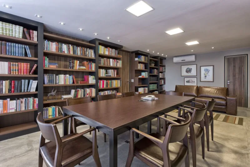 Para comportar o acervo de livros de um escritório de advocacia, as arquitetas Olga Bergamini, Karin Neitzke e Danielle Bragagnolo desenharam essa estante em MDF de parede inteira, com volumes e profundidades variadas. Foto: Marcelo Stammer/Divulgação