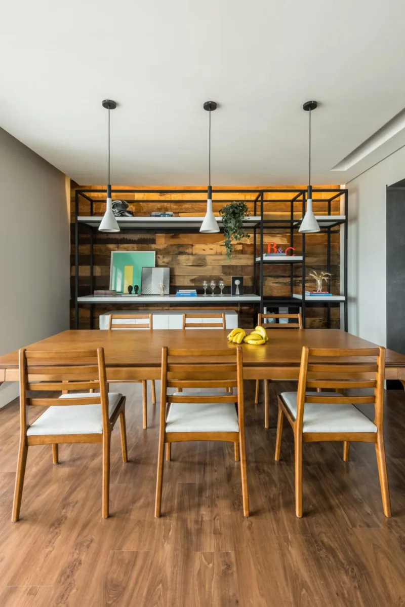 Na sala de jantar dos clientes de Ana Carolina e Corsi, as diferentes alturas das prateleiras garantem funcionalidade total. Os materiais do móvel - ferro e MDF - e do painel ao fundo - madeira de demolição - foram repetidos no outro ponto de fuga do ambiente.
