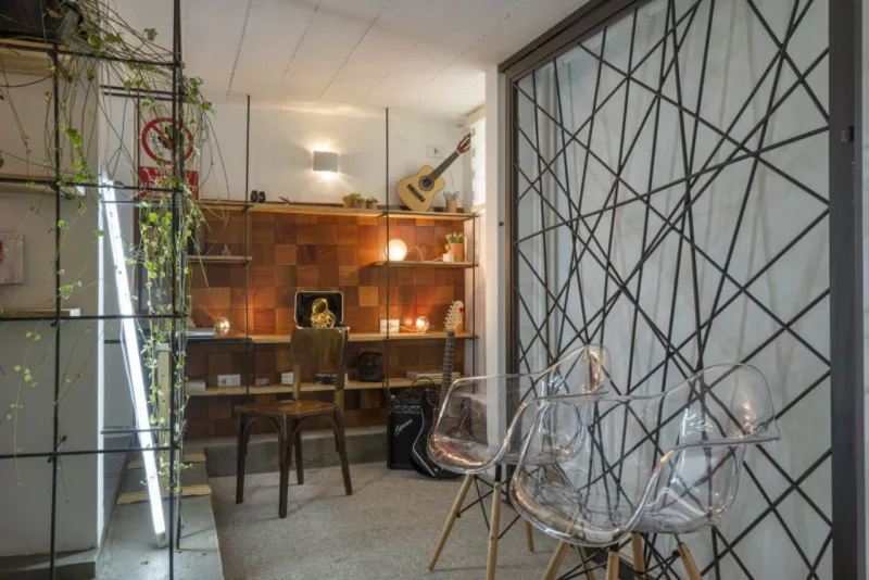 Vergalhões de construção fixos no piso e no teto e chapas de compensado naval formam a estante criada pelo Estúdio Campetti. Instalada em uma pequena parede de um porão, foi ambientada como uma sala de música, mas poderia ser uma opção para “um espaço pequeno como um fundo sem uso de corredor”, aponta Tiago Campetti. Por ser um porão, o lugar tinha uma atmosfera fria e pedia um toque de aconchego, garantido pelo painel feito com pastilhas de madeira ao fundo da estante. Outro toque que faz a diferença é a luz vinda de vários pontos. “O jogo de iluminação resultante e os vergalhões criam um clima interessante, muito mais do que se a luz fosse direta”, afirma ele. Foto: Fernando Zequinão/Gazeta do Povo