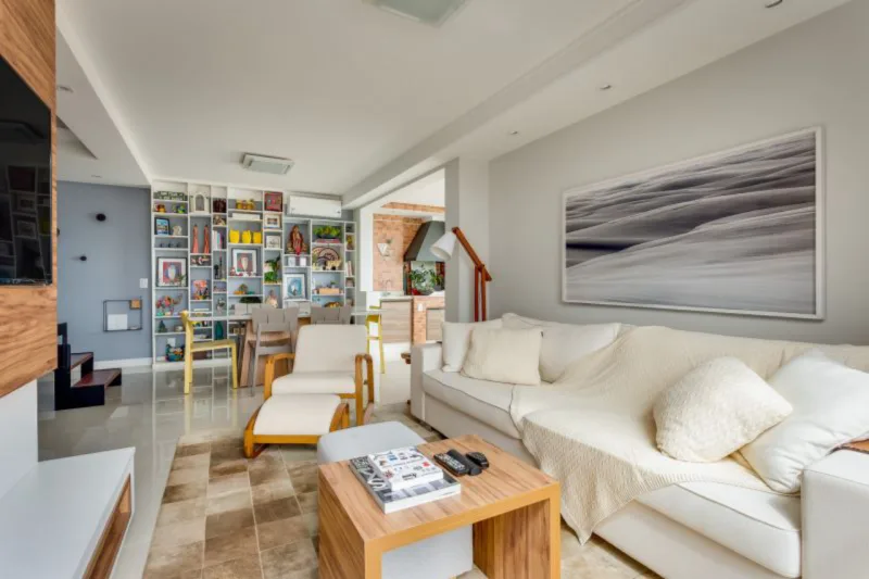 Objetos afetivos, como um móvel herança da família, são valorizados no hygge. Felipe Bender valorizou na sala a estante da cliente, repleta de lembranças de viagens pelo mundo. Crédito: Bender Arquitetura/Divulgação.