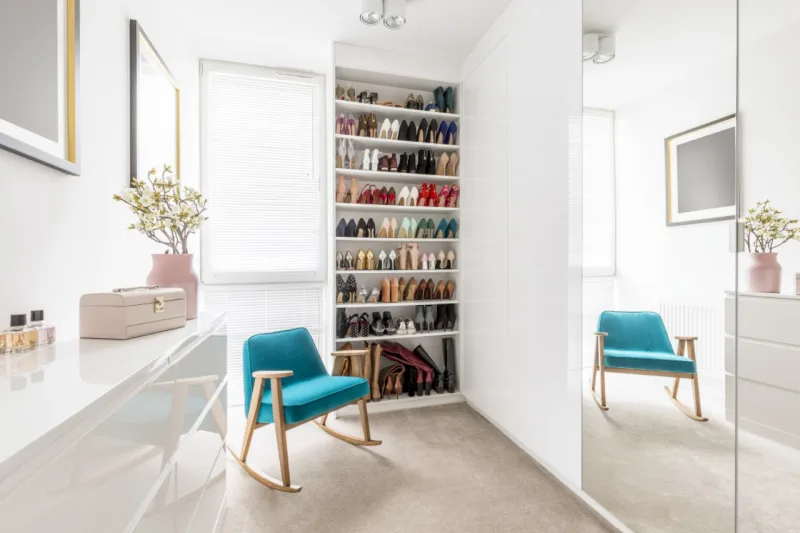 Dreamy feminine wardrobe with white furniture big mirror shoe closet beige carpet blue retro armchair and pastel pink accessories