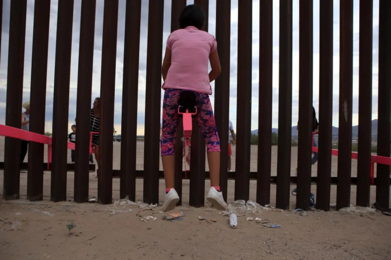 American and Mexican families play with a toy called "up and down" (Seesaw swing) over the Mexican border with US at the Anapra zone in Ciudad Juarez, Chihuahua State, Mexico on July 28, 2019. (Photo by LUIS TORRES / AFP)