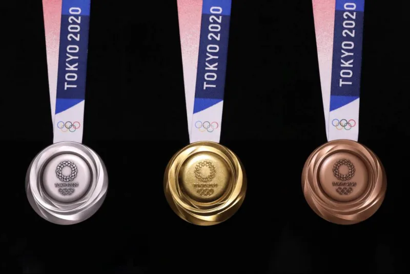 Com 8,5 cm de diâmetro, a parte da frente mostra os anéis olímpicos e o logotipo da Tóquio-2020. A parte de trás apresenta Nike, a deusa grega da vitória, no estádio Panathinaiko, em Atenas. Foto: Olimpíadas de Tóquio de 2020/AFP