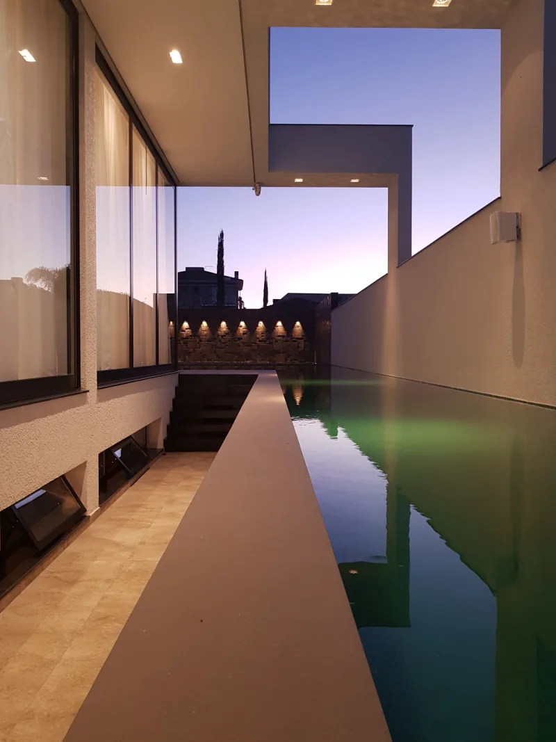 Piscina é revestida em azulejo verde e tem borda de cimento e deck de madeira. Foto: Divulgação