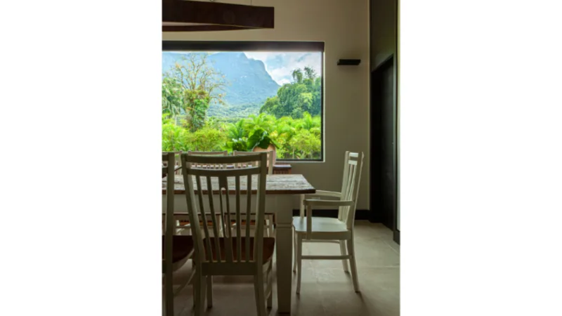 Grande abertura em frente à mesa de jantar da casa emoldura a vista principal do terreno: o Pico do Marumbi.