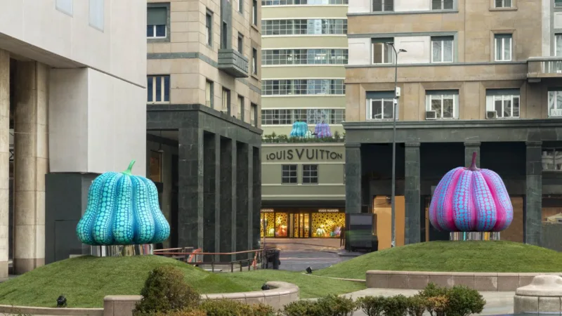 As abóboras gigantes, uma das marcas registradas de Yayoy Kusama, instaladas na praça San Babila e a nova loja da maison (ao fundo).
