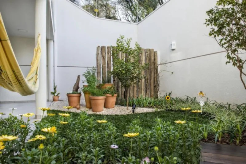 A paisagista Claudia Canales deu alma de interior aos fundos de uma casa com diversas flores e árvores frutíferas