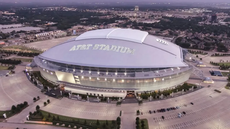AT&T Stadium, Texas (EUA). Assinado pelo HKS, tem capacidade para 80 mil pessoas, mas pode ser expandido para 100 mil pagantes. O teto, retrátil,  é apoiado em um par de arcos de 91 metros de altura.