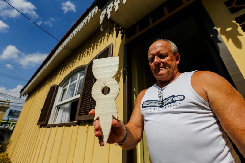 Gilberto Mafazolli mostra com carinho a "matriz" de um lambrequim igual ao que adorna a casa construída por seu avô. Foto: Jonathan Campos / Gazeta do Povo