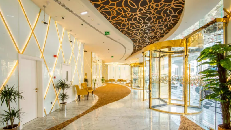 Lobby do hotel tem diversos detalhes em ouro e decoração com inspiração art déco.