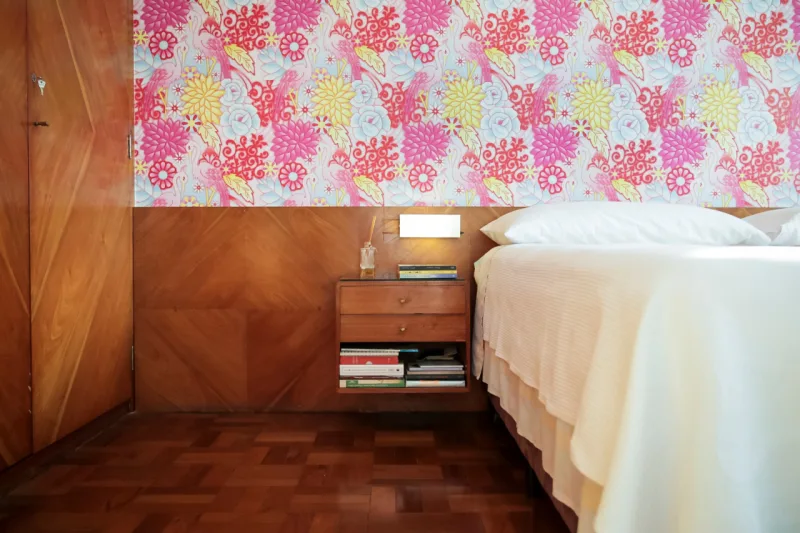 Detalhe do quarto: painel de madeira e papel de parede reforçam a linguagem do projeto.
