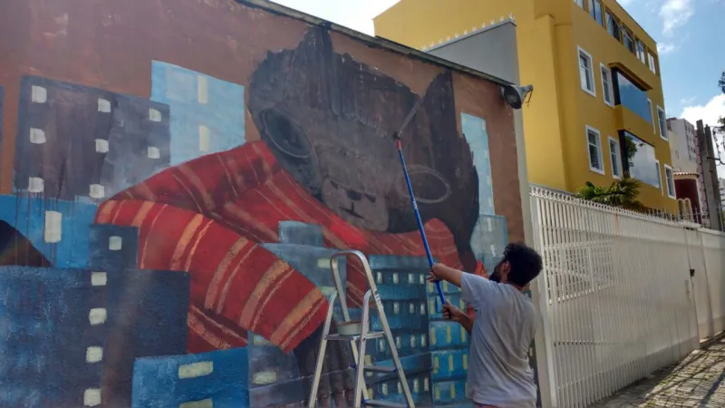 O artista urbano Thiago Goms finaliza a obra que fez na Alameda Prudente de Moraes, em frente a Ôda Design Club.
Foto: Daliane Nogueira / Gazeta do Povo