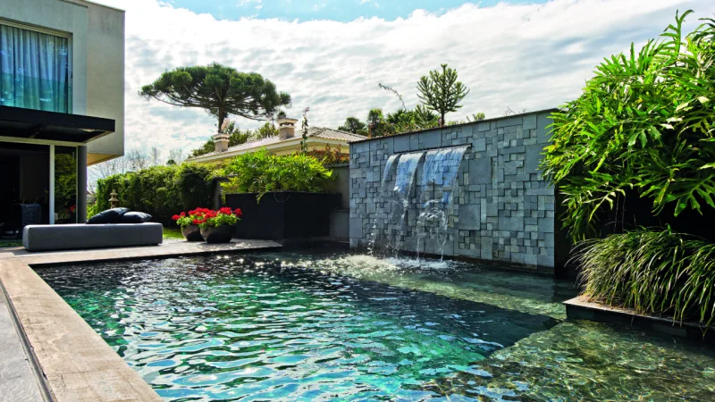 Revestimento em pedra cria ambiente que remete a uma piscina natural.