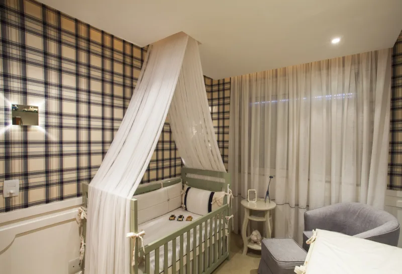 Berço verde e papel de parede xadrez completa o ambiente clássico.