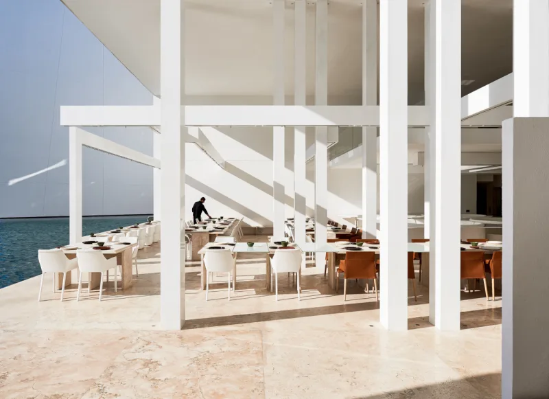 Um dos restaurantes é praticamente todo branco, o que leva a atenção para a paisagem e vigas aparentes.