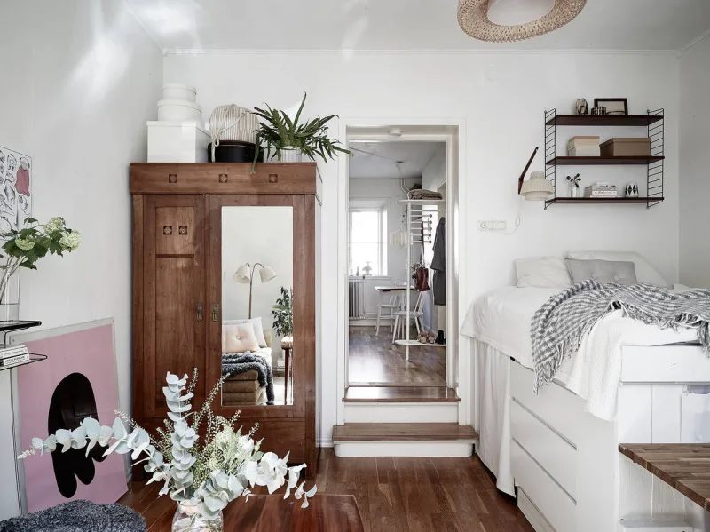Um guarda-roupa com madeira semelhante ao piso o deixa praticamente invisível ao lado da porta. Dois degraus levam à cozinha, por onde se entra no apartamento.