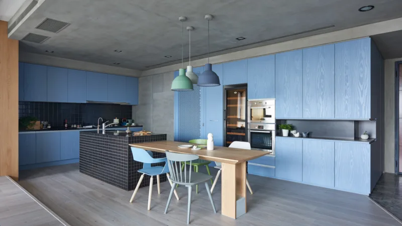 Na cozinha, os armários em azul-céu têm veios sutilmente visíveis. Os pendentes em estilo escandinavo seguem a cartela de cores.