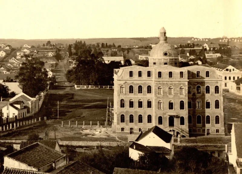 Edifício da UFPR em construção em 1912, com uma chácara ao fundo, onde hoje é o Teatro Guaíra.
Volk/Acervo Paulo José da Costa