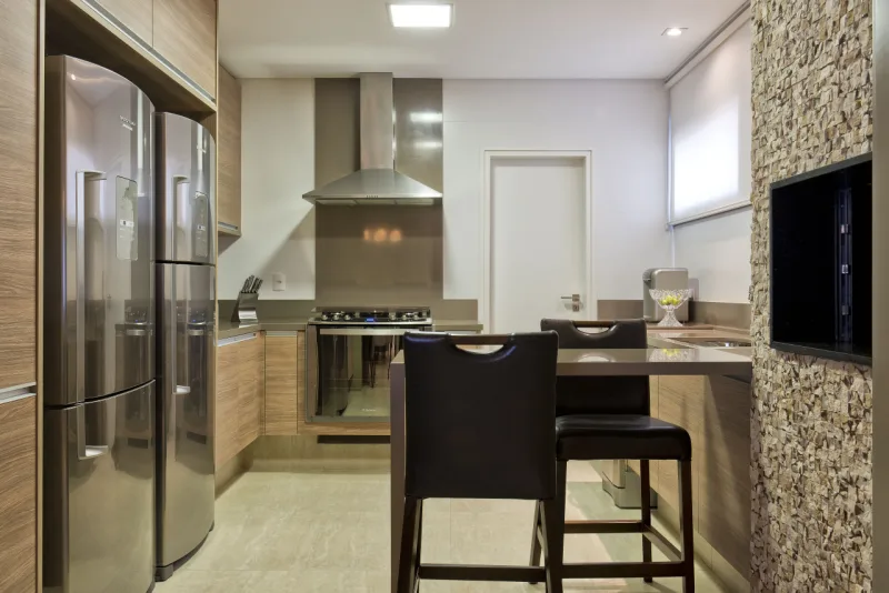 Detalhe da cozinha com móveis claros e eletrodomésticos em aço inox.