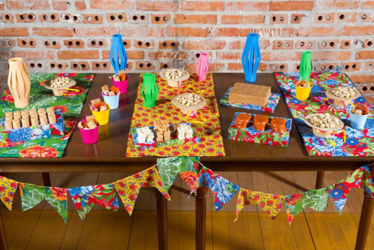 Faça a caixinha com a chita e aproveite os retalhos para compor a mesa cheia de doces. Enfeite com bandeirinhas de tecido, balões feitos de papel ou EVA e chapéus de palha para bonecos, que servem de potinhos para guloseimas. Os materiais podem ser encontrados em casas de embalagens. Fotos: Fred Kendi/Gazeta do Povo