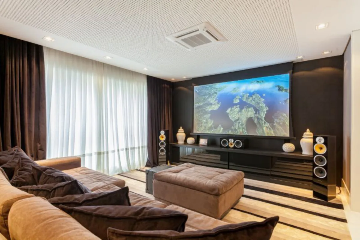 Projeto de Viviane Loyola com sistema completo instalado pela Euro Áudio. Teto com revestimento acústico, cortinas escuras e sofá retrátil ajudam a criar o clima de cinema. Os equipamentos são de ponta e o investimento foi de cerca de R$ 100 mil