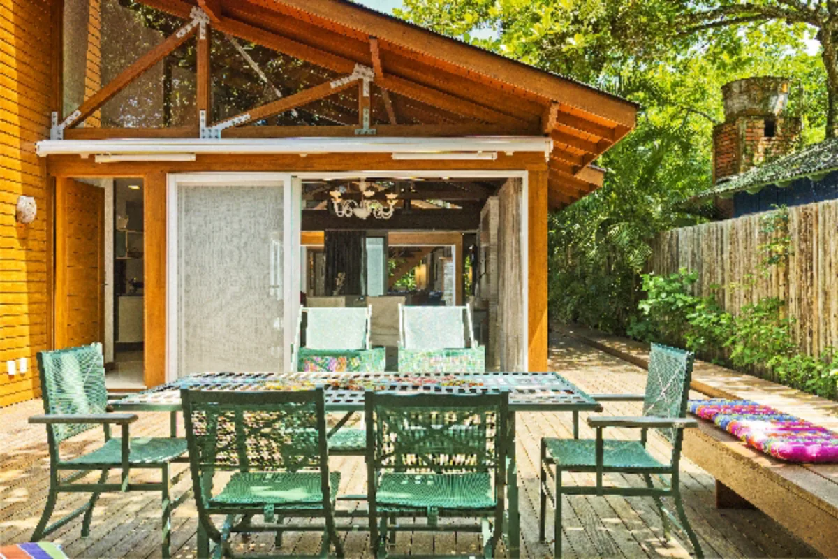 Fachada e varanda: Madeira natural e vidro na fachada reforçam o conceito ecológico e estabelecem uma conversa entre a construção e a paisagem. A mesa de jantar na varanda é a prova da integração entre os ambientes internos e externos. As áreas íntimas da casa, no entanto, foram separadas das sociais para garantir a privacidade da família