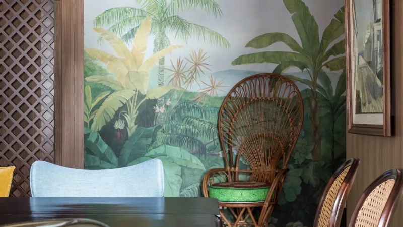 Para trazer mais personalidade, a arquiteta usou um papel de parede de estampa tropical e a poltrona Peacock