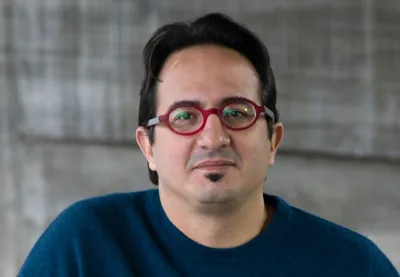 Primeiro plano de Fernando Serapião, homem branco, de cabelos pretos, e óculos redondos vermelhos
