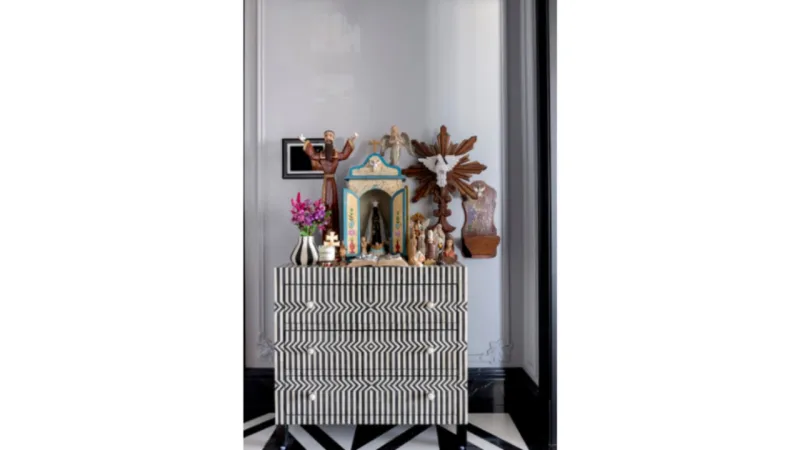 O projeto de design de interiores inseriu um altar com os santos da cliente, em cômoda de osso da loja Maria Pia.