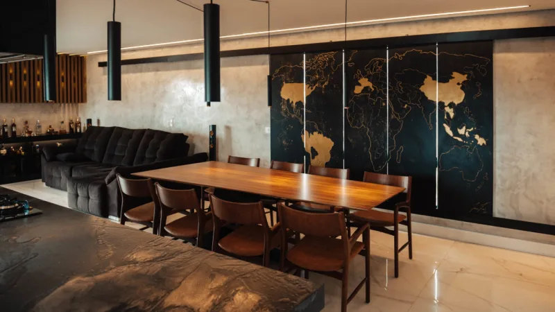 O painel metálico é o grande destaque do apartamento. É tanto uma peça de arte quanto um blackout para a janela. Com uma ilustração de mapa-múndi, tem em dourado os países já visitados pelo proprietário.