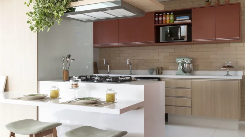 Cooktop foi instalado na península branca para liberar espaço na área do tampo e permitir que o cozinheiro fique de frente para as visitas. Para aproveitar melhor o espaço, uma bancada também foi integrada à península — solução funcional é ideal para refeições rápidas, como o café da manhã.